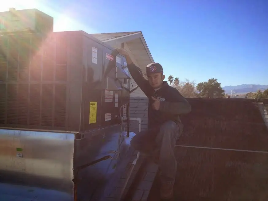 HVAC technician performing Air Duct Repair on a rooftop unit in Beverly