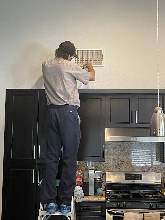 Technician inspecting an air vent during HVAC service in Beverly